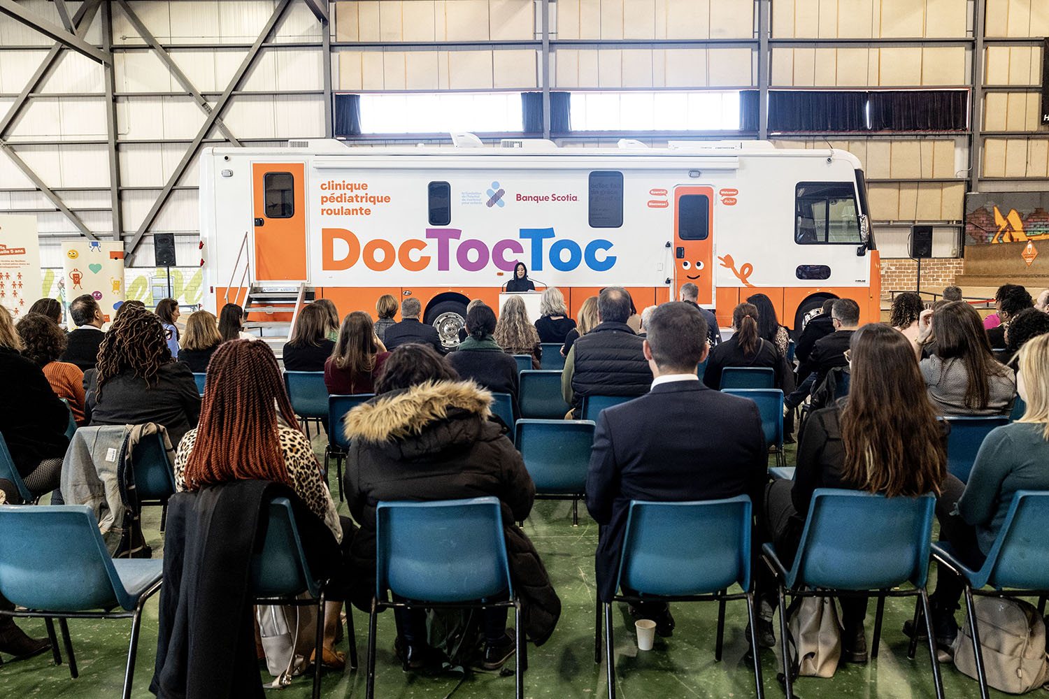 Une centaine d'invités assis face à la clinique mobile DocTocToc pendant les allocutions