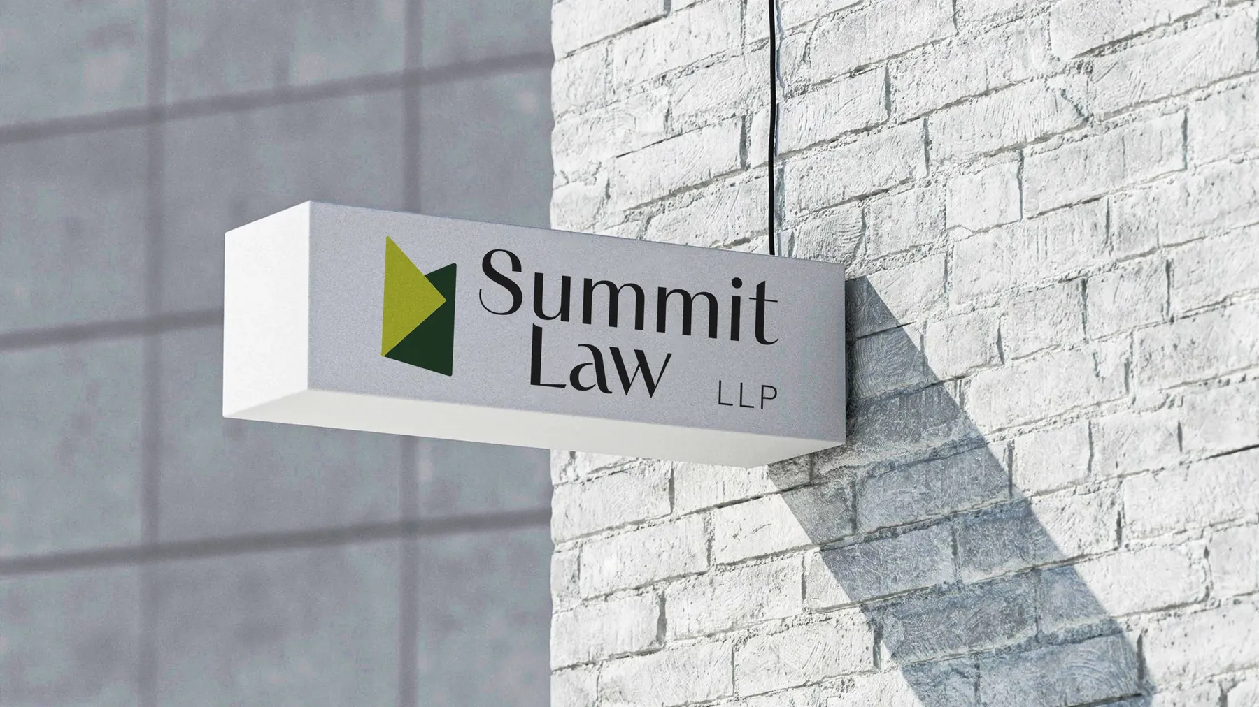 Enseigne murale Summit Law LLP sur un mur de brique blanche, en lumière rasante