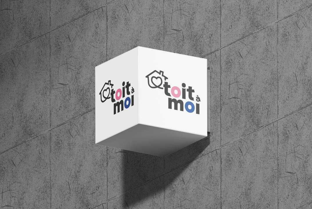Enseigne cubique blanche portant le logo de Toit à moi sur un mur de béton