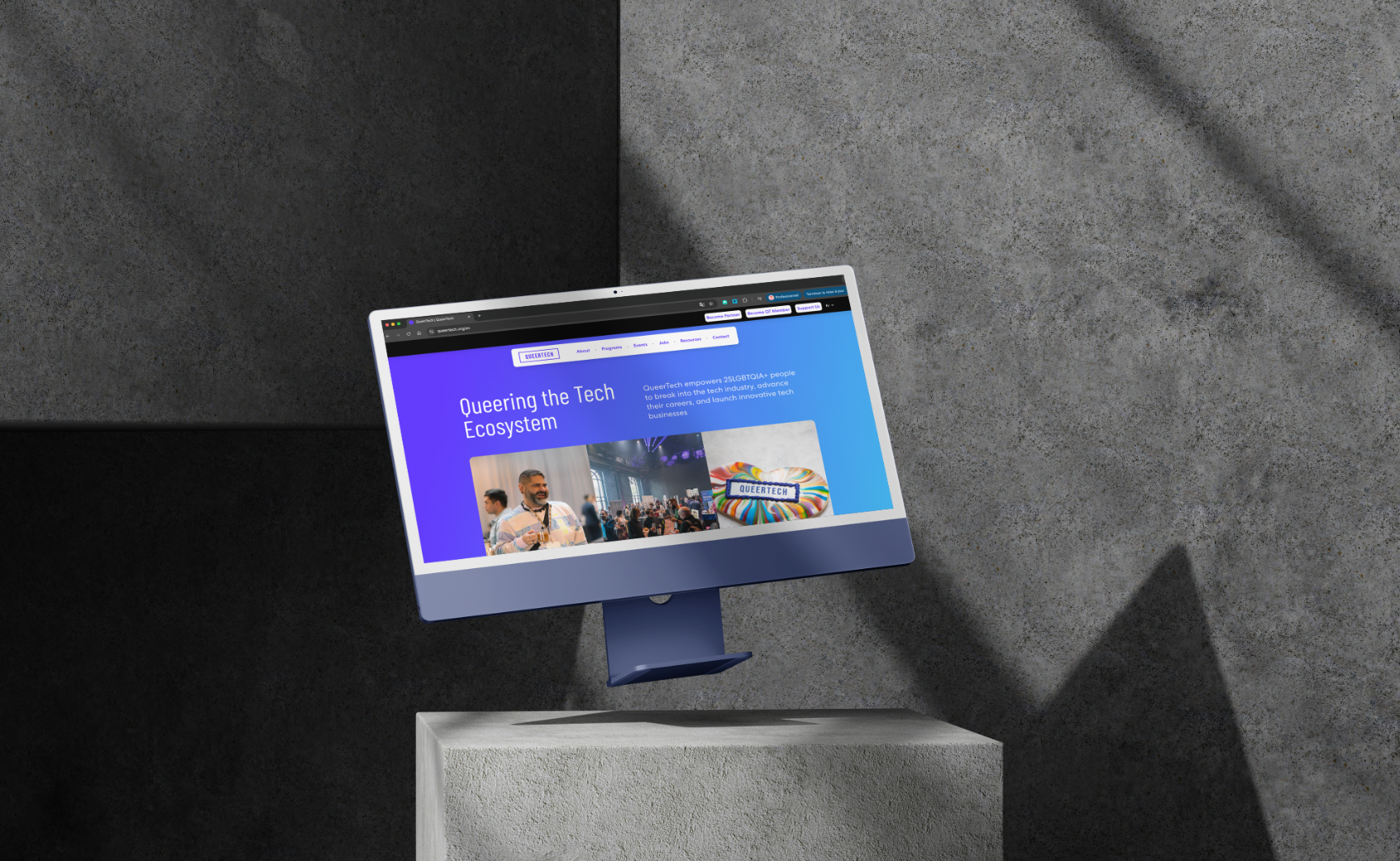 Écran desktop affichant la page d'accueil de QueerTech, dans un décor de béton